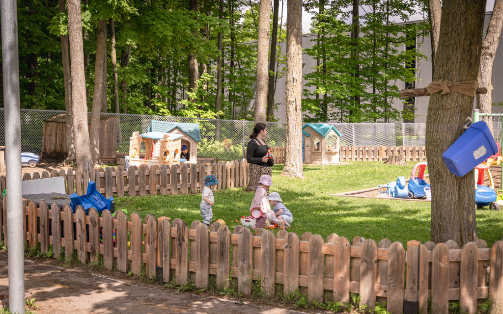 Une éducatrice surveille les petits enfants en train de jouer dehors