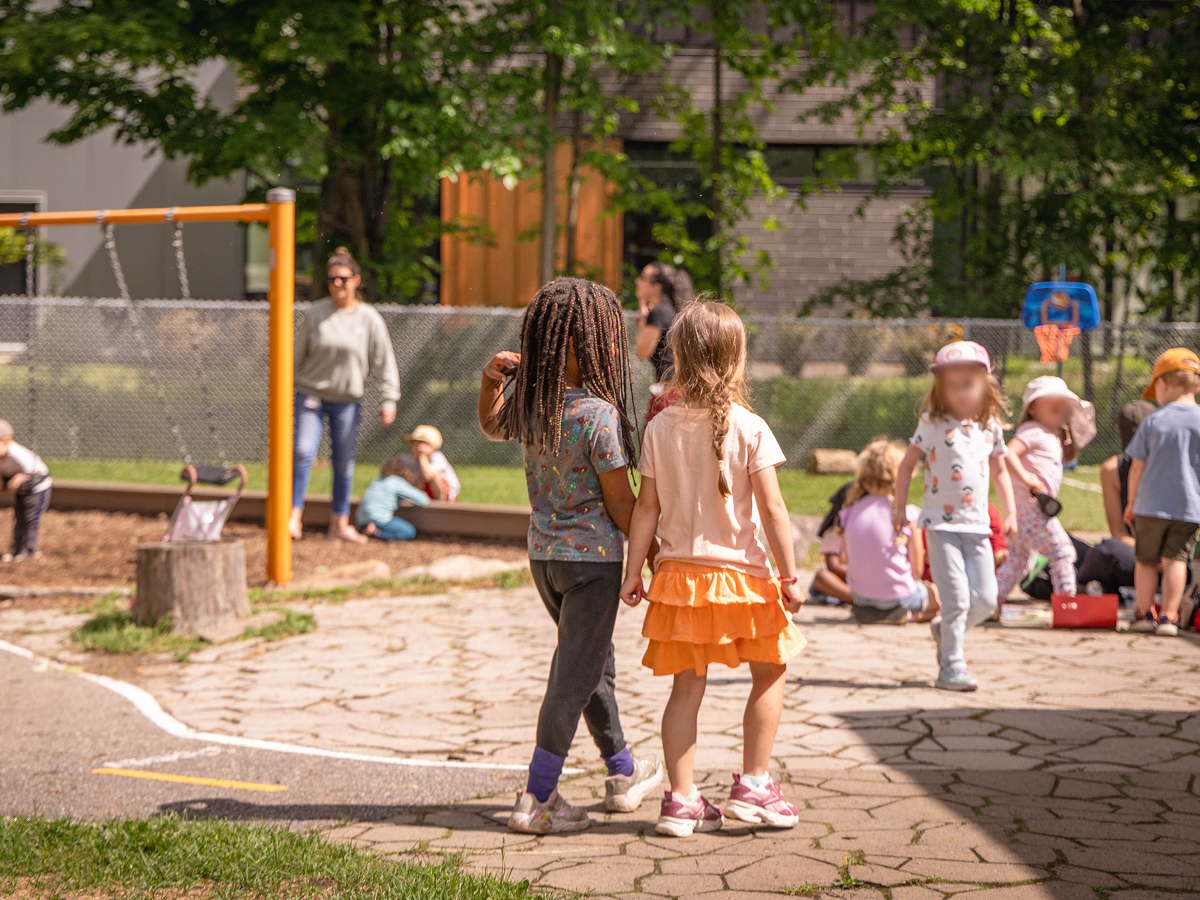Deux petites filles se tiennent par la main dans la cour extérieure